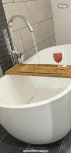 a bath tub with a glass of wine sitting on top at Newton house in Burton Fleming