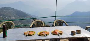 a table with plates of food on top of a mountain at The Shire Snower in Kulu