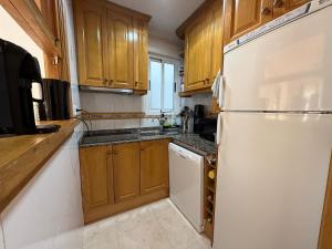 a kitchen with wooden cabinets and a white refrigerator at Apartment in Strandnähe in Guardamar del Segura