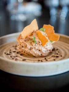 a bowl of dip with chips and crackers on top at Saint Aubin Logis Hôtel & Restaurant in Saint-Aubin-sur-Mer