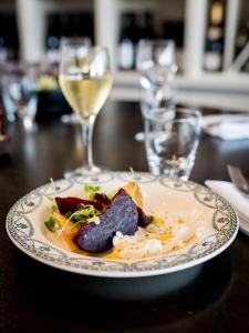 a plate of food on a table with wine glasses at Saint Aubin Logis Hôtel & Restaurant in Saint-Aubin-sur-Mer