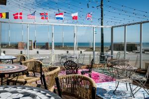 a patio with tables and chairs and flags at Saint Aubin Logis Hôtel & Restaurant in Saint-Aubin-sur-Mer