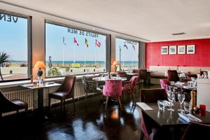 a restaurant with tables and chairs and a view of the beach at Saint Aubin Logis Hôtel & Restaurant in Saint-Aubin-sur-Mer