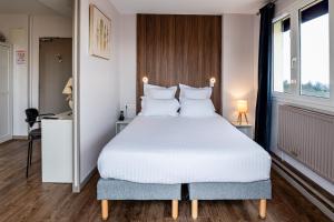 a bedroom with a large white bed with white pillows at Saint Aubin Logis Hôtel & Restaurant in Saint-Aubin-sur-Mer
