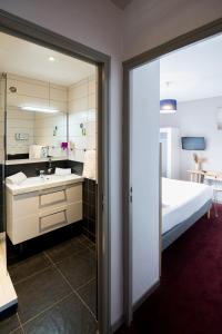 a bathroom with a sink and a bed and a mirror at Saint Aubin Logis Hôtel & Restaurant in Saint-Aubin-sur-Mer +37 photos