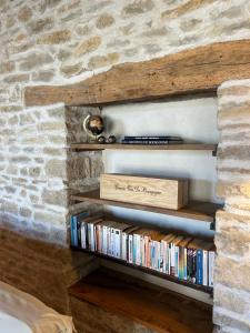 a book shelf filled with dvds next to a stone wall at Le Refuge Bourguignon in Nuits-Saint-Georges