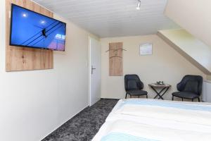 a bedroom with a bed and two chairs at Pension Burggaststätte Heyken in Neuharlingersiel