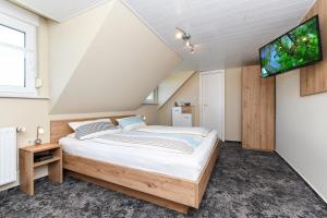 a bedroom with a bed and a flat screen tv at Pension Burggaststätte Heyken in Neuharlingersiel