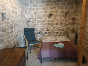 1 dormitorio con 1 cama y 1 silla en una pared de piedra en Charmant LOFT, en Draguignan 1 foto más