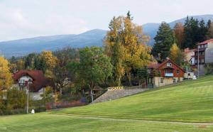 ein grünes Feld mit einem Haus und einem Zaun in der Unterkunft Gosciniec Poezja in Szklarska Poręba