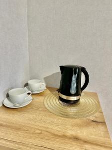 a black tea kettle and two cups on a wooden table at Poziom 4 - Prywatny prysznic, wspólne WC in Katowice +62 photos
