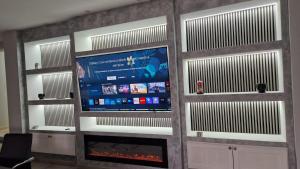 Una sala de estar con televisión y chimenea. en Villa GEMMA, en Castel Volturno