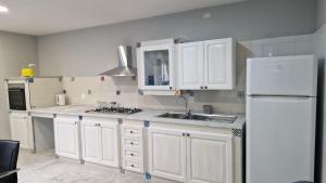 a kitchen with white cabinets and a sink and a refrigerator at Villa GEMMA in Castel Volturno