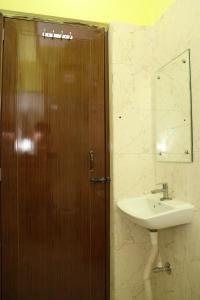 a bathroom with a wooden door and a sink at Park kasba Inn in Kolkata