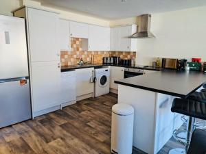 a kitchen with white cabinets and a washer and dryer at Clyde Cottage in Lamington