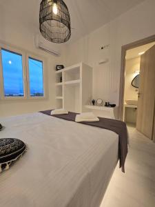 een witte slaapkamer met een groot wit bed en ramen bij Magia's Residence in Naousa
