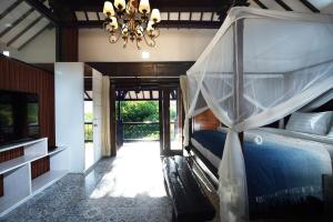 a bedroom with a bed with a canopy and a chandelier at 3BR Pool Villa, Canggu, River View in Dalung
