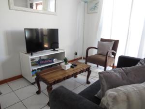 a living room with a tv and a coffee table at Chamomile Cottage in Muizenberg