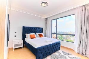 a bedroom with a blue bed with a large window at Riara One Residency, Kilimani in Nairobi +32 photos