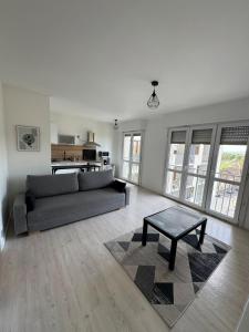 a living room with a couch and a coffee table at Grand studio lumineux proche gare in Saint-Ouen-lʼAumône