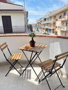 un tavolo e sedie su un balcone con una pianta in vaso di STELLA MARINA Apartment a Mascali Altre 31 foto