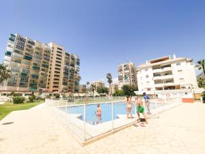 grupa ludzi stojących wokół płotu wokół basenu w obiekcie Vistas al mar a 1 min de playa con parkig gratis w mieście Benalmádena