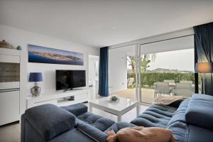 ein Wohnzimmer mit einem blauen Sofa und einem Fernseher in der Unterkunft Mijas Tres Caminos in La Cala de Mijas