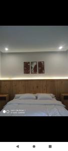 a bedroom with a bed with two pictures on the wall at Green cottage in Labuan Tring +10 photos