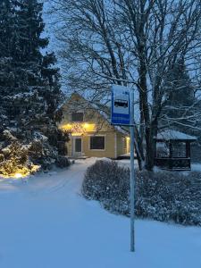 a blue sign in the snow in front of a house at Puuna Öömaja B&B in Vihterpalu +7 photos