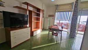 Una sala de estar con una mesa de comedor y un televisor. en Tramonto, en Porto Cesareo
