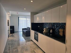 a kitchen with white cabinets and a blue couch at Mercury Suites - Skydream Getaways in St. Julianʼs