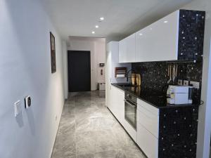 a kitchen with white cabinets and black counter tops at Mercury Suites - Skydream Getaways in St. Julianʼs
