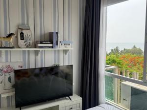a living room with a flat screen tv and a window at The Blu X Ocean view Family top floor in Ban Bang Saen (1)