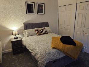 a bedroom with a bed and a nightstand with a lamp at Addex Apartment in Dunfermline