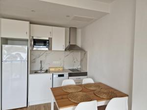 a kitchen with a wooden table and white cabinets at Mirada Ponent in Es Pujols