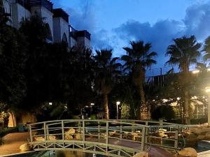 a bridge over a pond in a park with palm trees at alamari gardens in Irbid