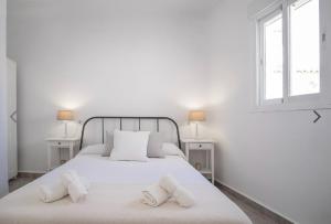a white bedroom with a white bed with two windows at Casco histórico de Estepona in Estepona