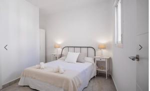 a white bedroom with a bed with two white towels on it at Casco histórico de Estepona in Estepona