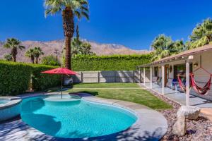 a swimming pool with a red umbrella and a playground at Kiwi Cottage Permit# 992 in Palm Springs