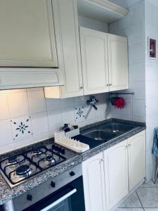 cocina con armarios blancos, fogones y fregadero en House 5 minutes walk from Vatican Museums, en Roma
