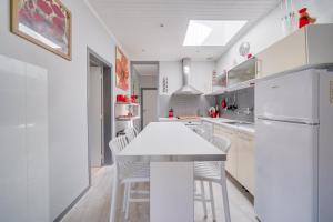 a white kitchen with a white table and chairs at Maison Papavero in La Teste-de-Buch