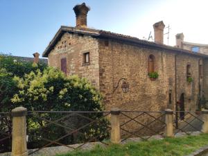 an old brick house with a fence in front of it at Locazione Gattapone 1A in Gubbio