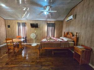 a bedroom with a bed and a table and a ceiling fan at Hibiscus Cabin with AC at Freshwater Creek Cabanas in Hopkins