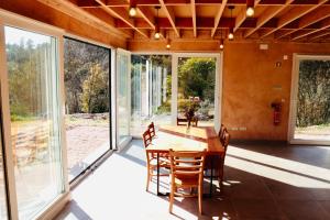 a dining room with a table and chairs and large windows at Ananda Guesthouse AL in Ourondo