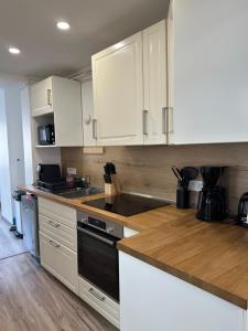 フェカンにあるCaptain YOO - Antre de Lupin - Relevez le défi !の白いキャビネットと黒い食器洗い機付きのキッチンが備わります。