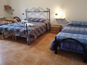 a bedroom with two beds and a wooden floor at La taverna del gufo bed & breakfast in Sarule