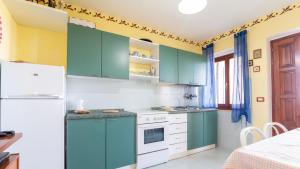 a kitchen with green cabinets and a white refrigerator at Casa Mare e Monti- Cuglieri in Cuglieri