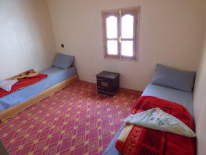 a small room with two beds and a window at gite taghia ahanssal in Taghia