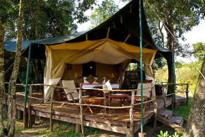 Mara Explorer Tented Camp في Aitong: خيمة مع كراسي وطاولة في الغابة