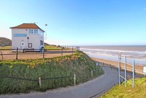 een gebouw aan de kant van een strand met de oceaan bij The Bee's Knees in Mundesley +14 foto's